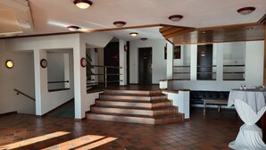 En rummelig lobby med trappe, reception og siddeområde.