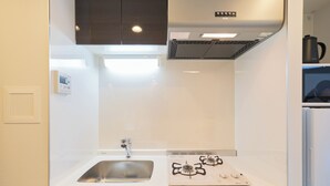 Une cuisine dotée d’un plan de travail blanc, d’un évier en acier inoxydable, d’une cuisinière à gaz et d’un four encastré.