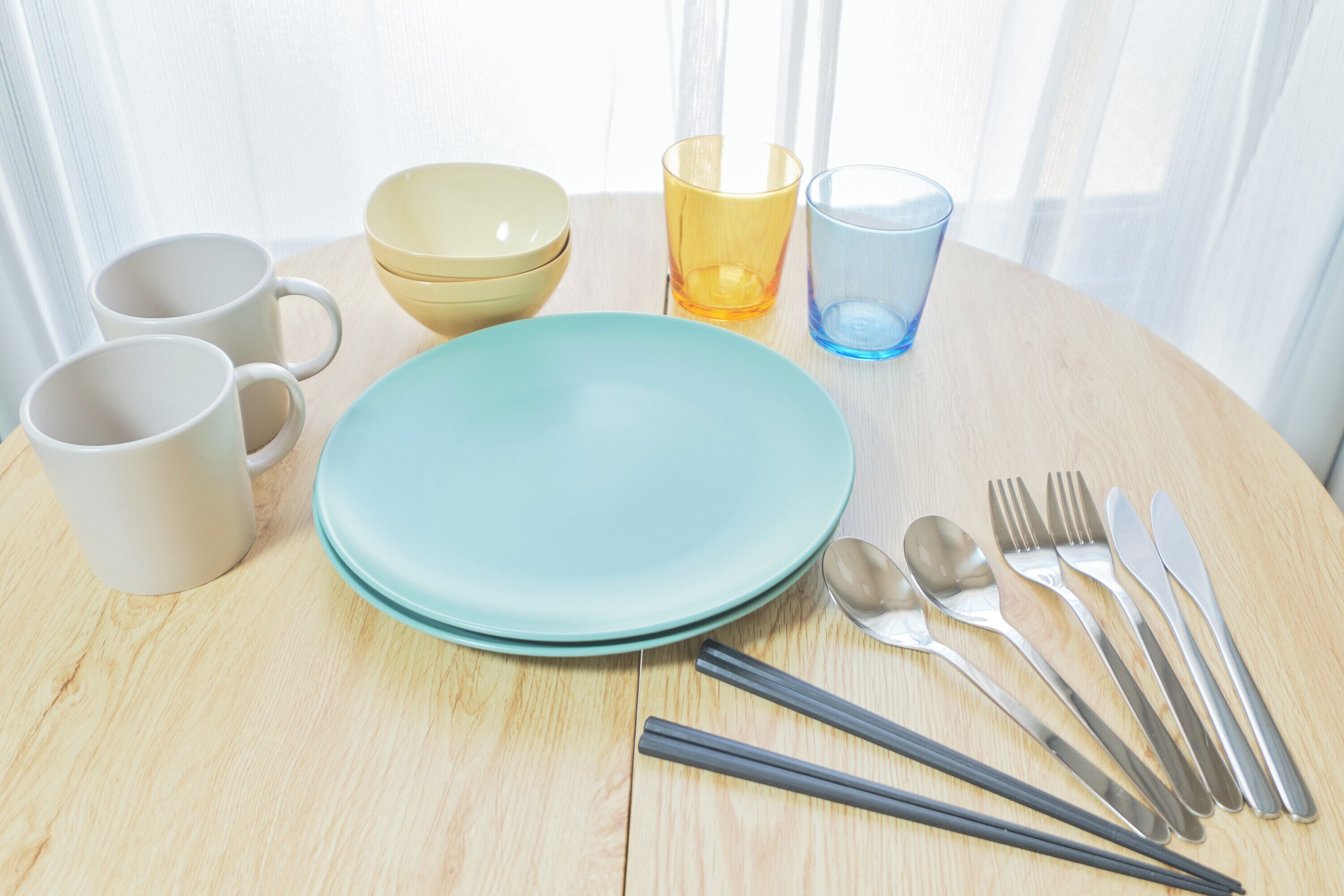 A dining table with plates, cups, cutlery, and glasses.