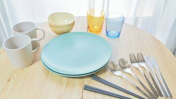 A dining table with plates, cups, cutlery, and glasses.