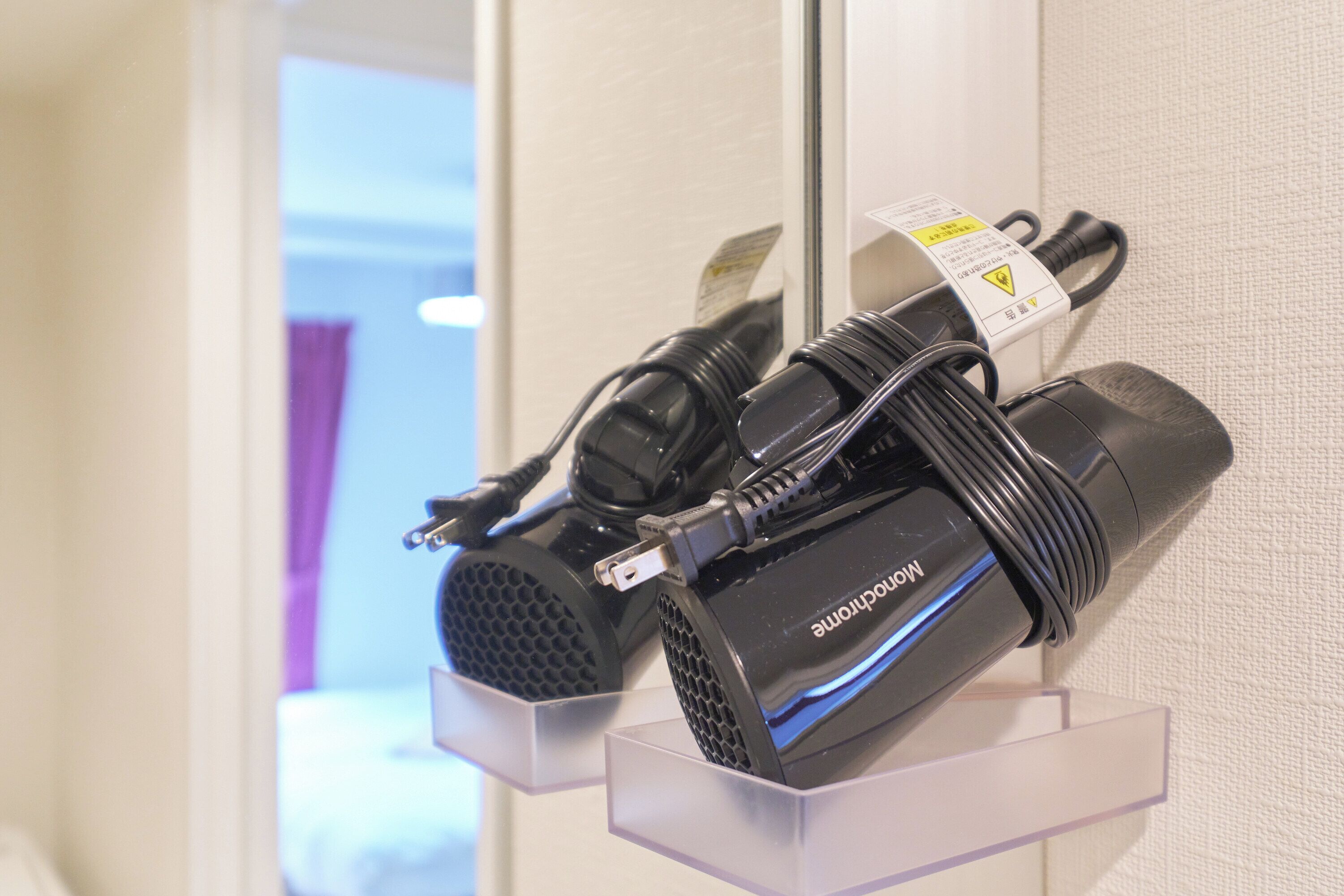 A hair dryer and its power cord on a display stand in a hotel room.