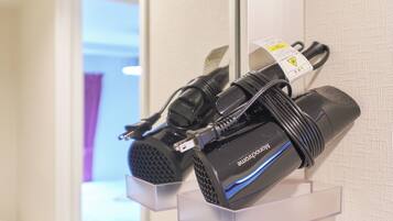 A hair dryer and its power cord on a display stand in a hotel room.