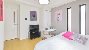 Une chambre d’hôtel moderne équipée d’un lit, d’une télévision, d’une petite table ronde et d’une chaise.