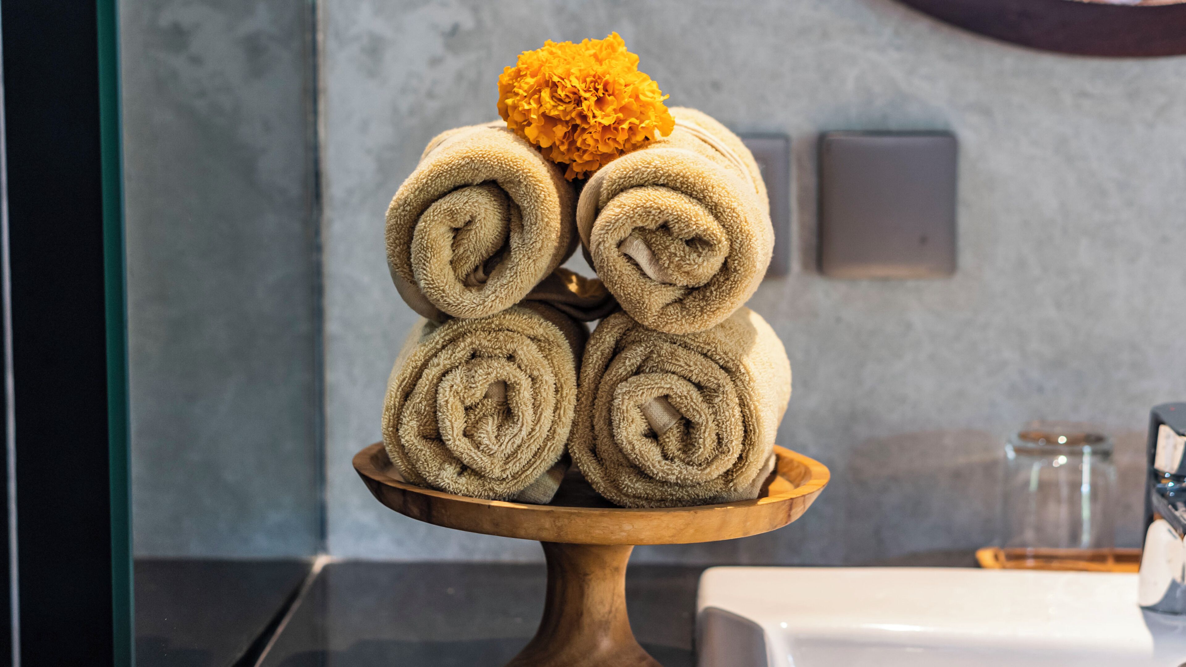 A stack of rolled towels on a wooden tray.