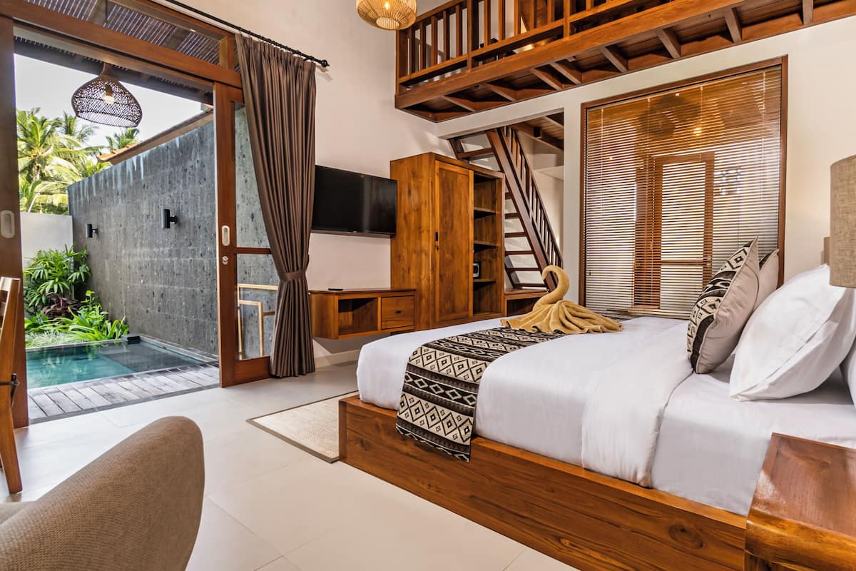Ein Schlafzimmer mit Bett, Fernseher, Holzschrank und Blick auf einen Pool.