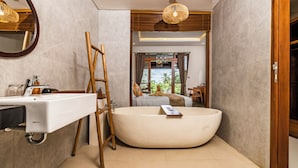 Un baño moderno con una bañera independiente, una escalera de madera y un espejo grande.