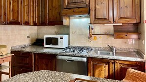 A kitchen with wooden cabinets, a microwave, a gas stove, and a dishwasher. - Beautiful apartment for 5 people with WIFI, TV, patio and pets allowed (Perledo)