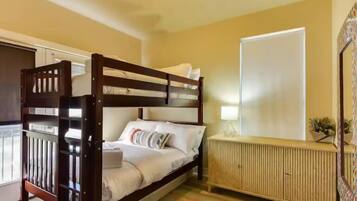 A bedroom with a bunk bed, a bedside table with a lamp, a radiator, and a window.