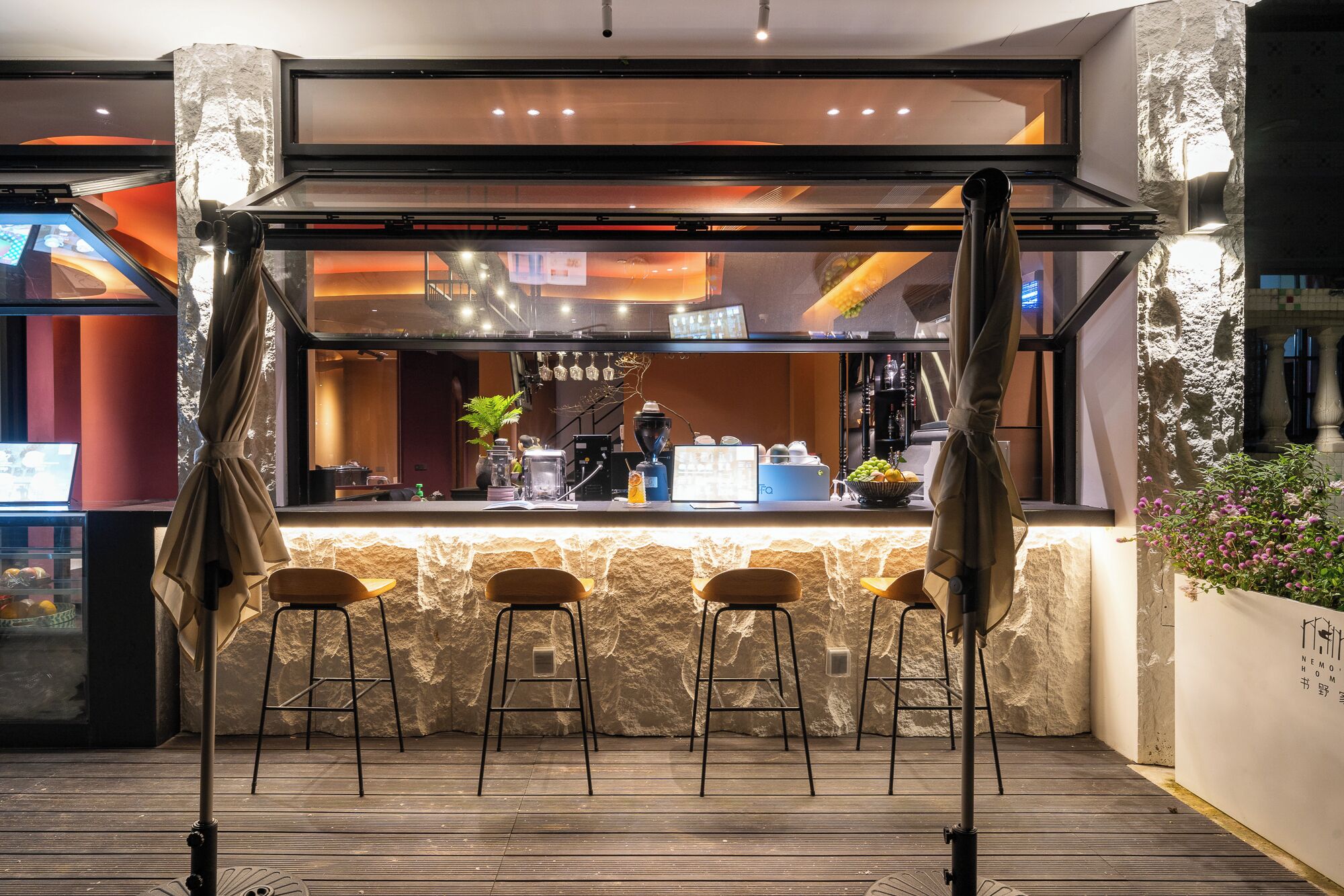 Uma área de bar com banquetas, balcão e vista do interior.