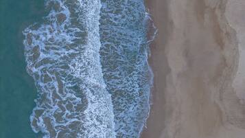 Vista aérea de uma praia com ondas quebrando na costa.