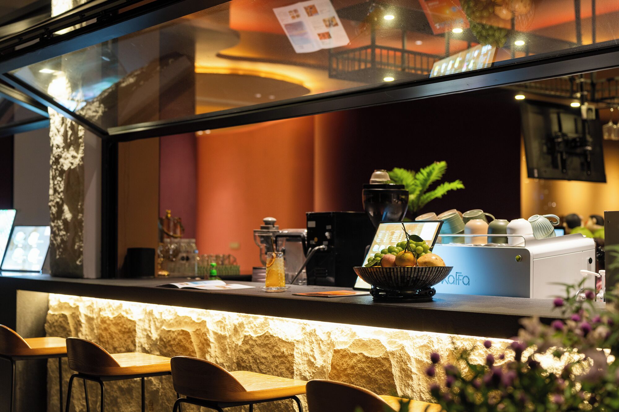 A bar area with a stone counter, a coffee machine, and a bowl of fruit.