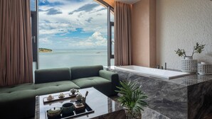 Ein modernes Zimmer mit einem großen Fenster, einem grünen Sofa, einer Marmorarbeitsplatte und einer Badewanne.