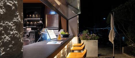 A bar area with a stone counter, bar stools, and a refrigerator.