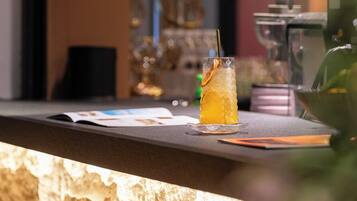 A bar area with a glass of iced drink, a menu, and a coffee machine.