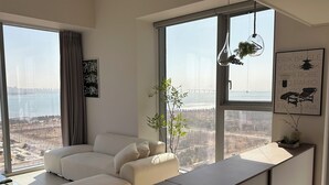 Een moderne woonkamer met een bank, een salontafel en een uitzicht op een stadslandschap door grote ramen.