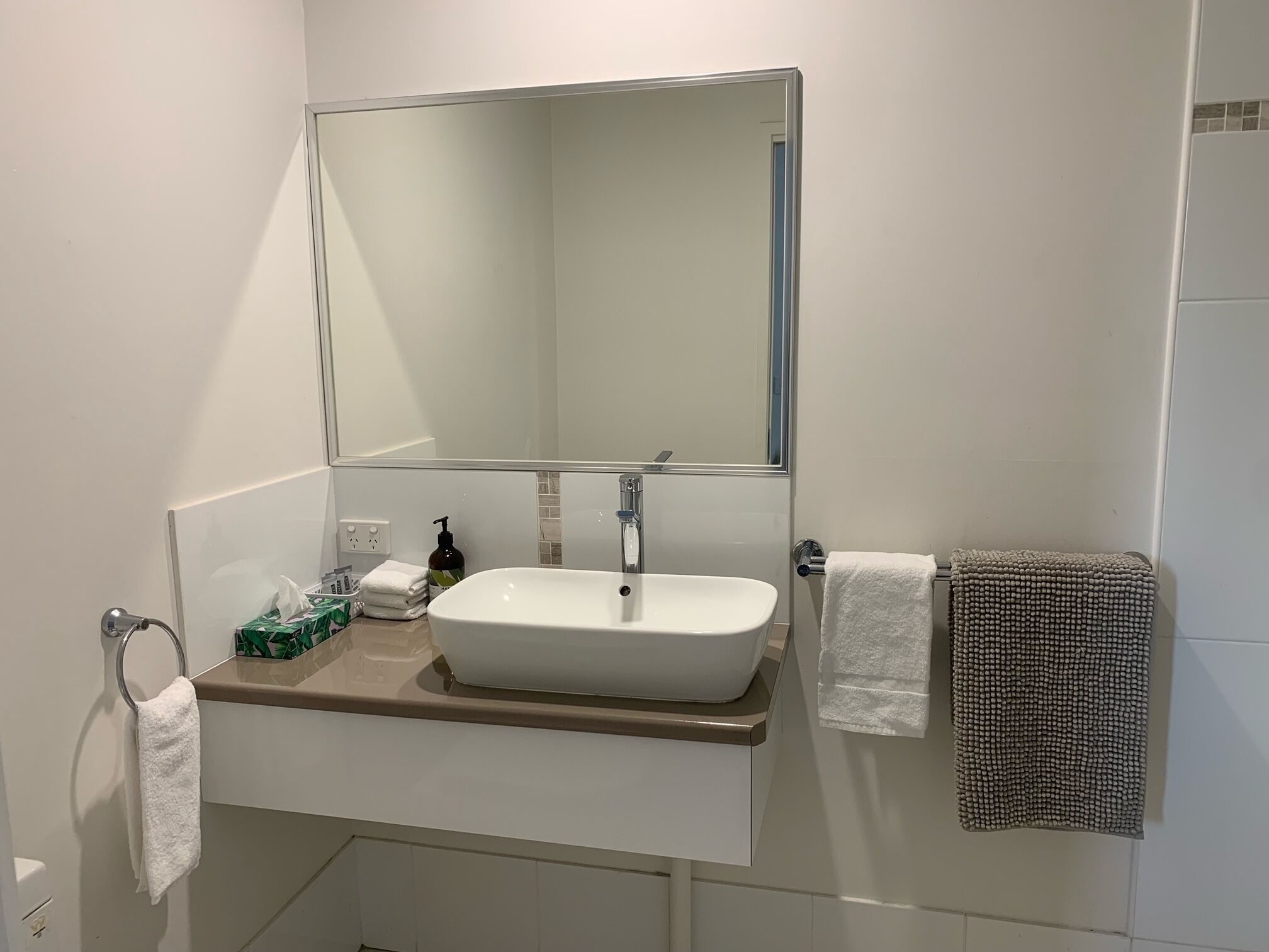 A bathroom with a white sink, a mirror, and a towel rack.