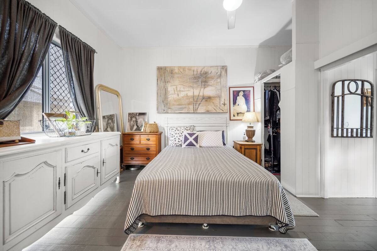 Ein Schlafzimmer mit Bett, Kommode, Spiegel und Bildern an der Wand.