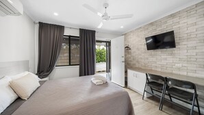 A modern hotel room with a bed, a desk, a chair, a TV, and a balcony. - Verandah Motel (Gympie)