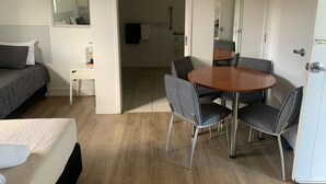 A hotel room with a bed, a small table, a round dining table with four chairs, a mirror, and a door with a no-smoking sign. - Verandah Motel (Gympie)