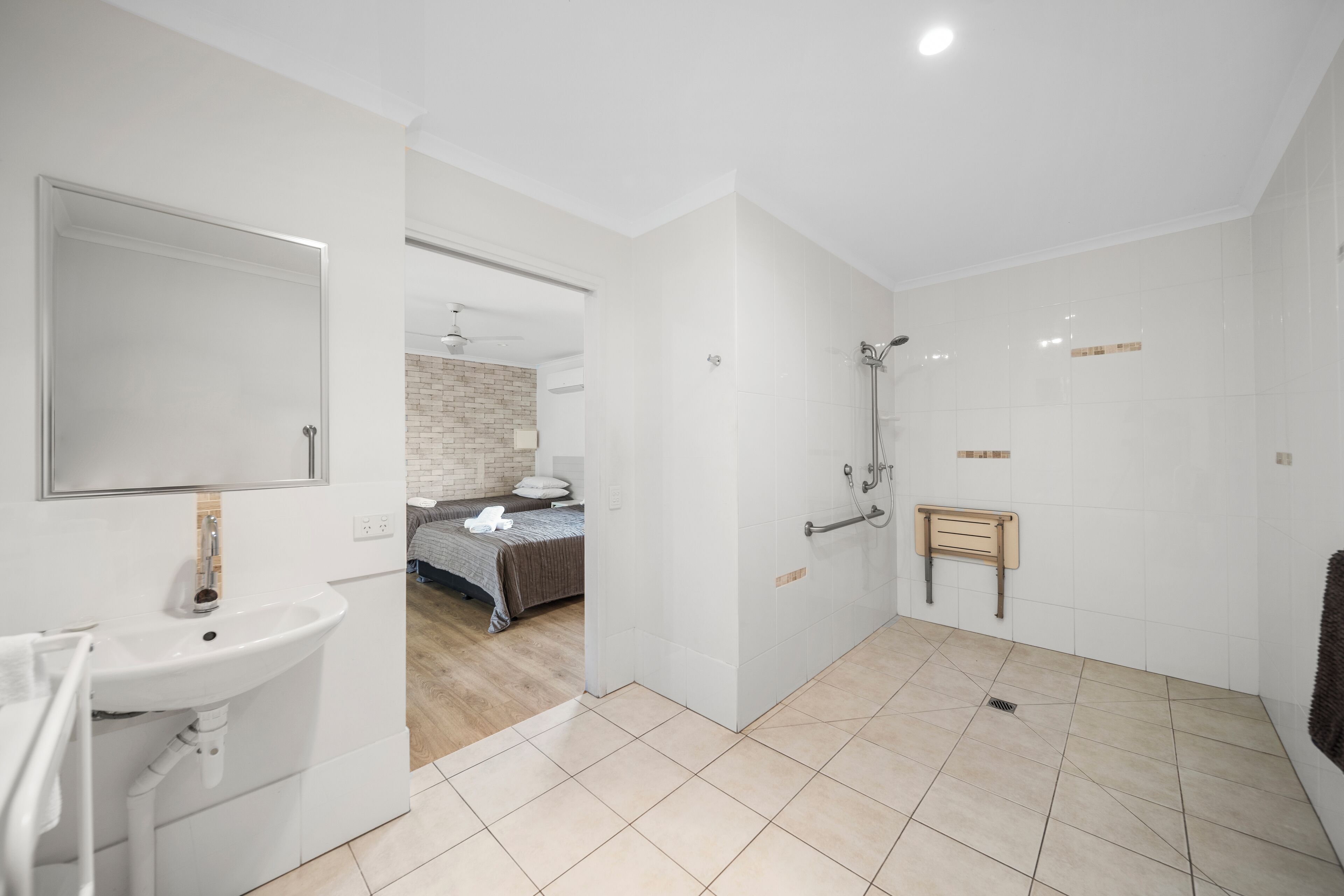 Un baño moderno con lavamanos, espejo y zona de ducha.
