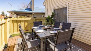 A backyard patio with a dining table set for four, surrounded by chairs.