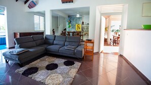 A living room with a grey sectional sofa, a patterned rug, and a wooden side table. - Enjoy the peace and quiet of nature in this fresh, bright villa. (Saint-Joseph)