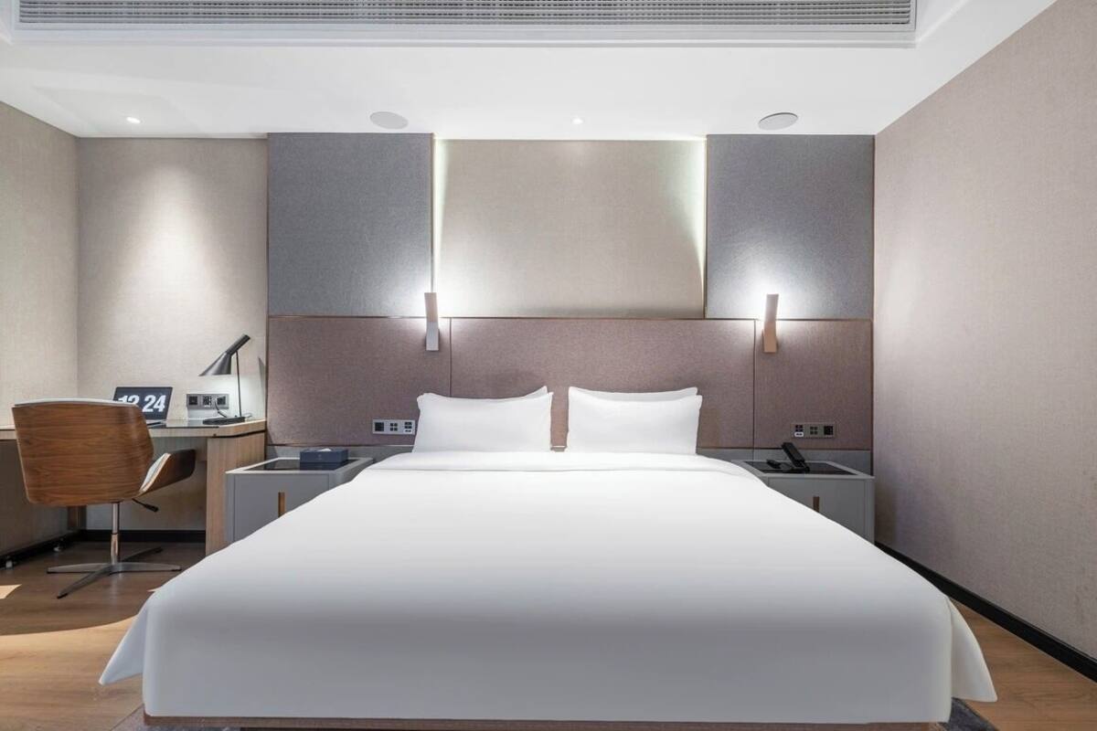 A modern hotel room with a large bed, bedside tables, a desk, and a chair.