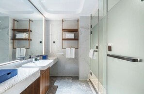 A modern bathroom with a large mirror, two sinks, wooden shelves, and a glass shower enclosure. - WANJIN HOTEL-Yongbin Overpass Subway (Nanning)