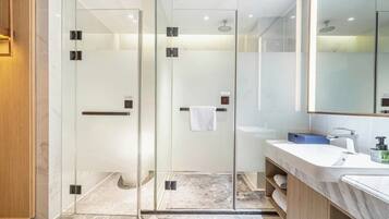 Un baño moderno con ducha envuelta en vidrio, un lavabo blanco y un espejo grande.