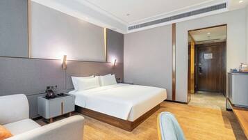 A modern hotel room with a large bed, bedside tables, a desk, and a chair.