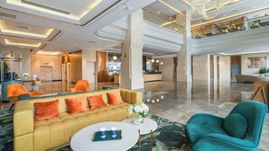 Eine großzügige Lobby mit einem gelben Sofa, einem türkisfarbenen Sessel und einem Couchtisch.