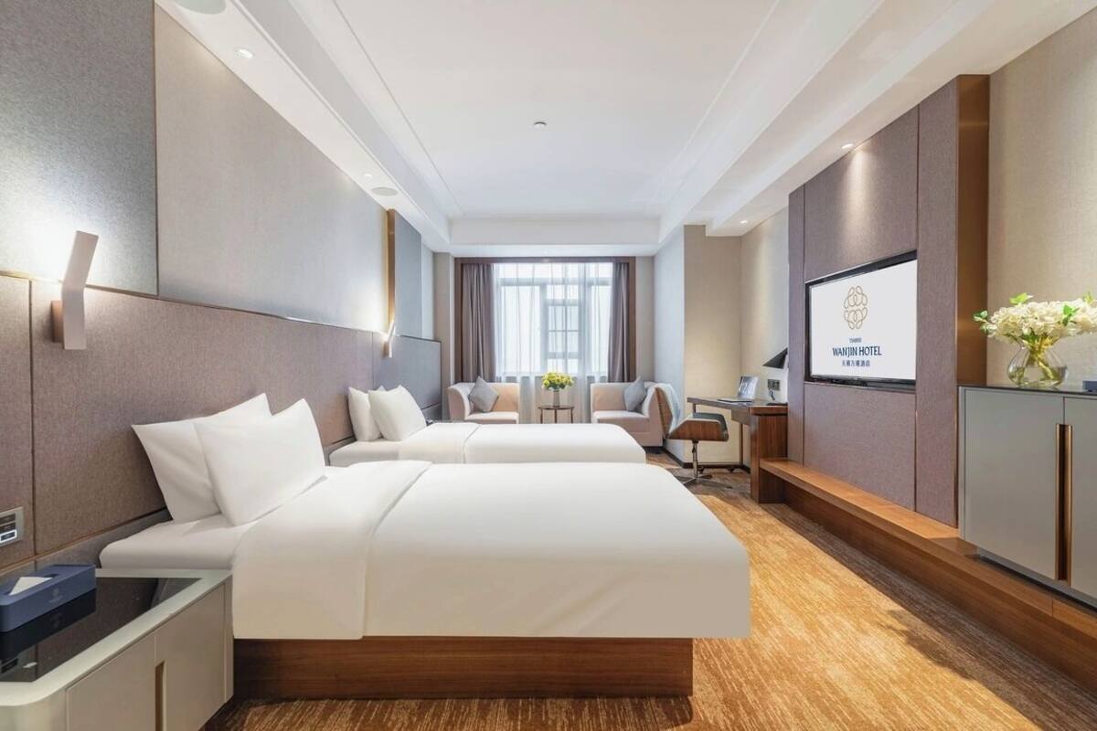 A hotel room with a large bed, a desk, a TV, and a view of the city.
