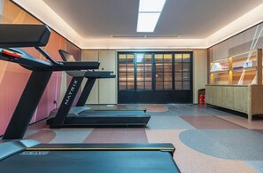 A modern gym with treadmills, a mirrored wall, and a sliding glass door leading to a balcony. - WANJIN HOTEL-Yongbin Overpass Subway (Nanning)