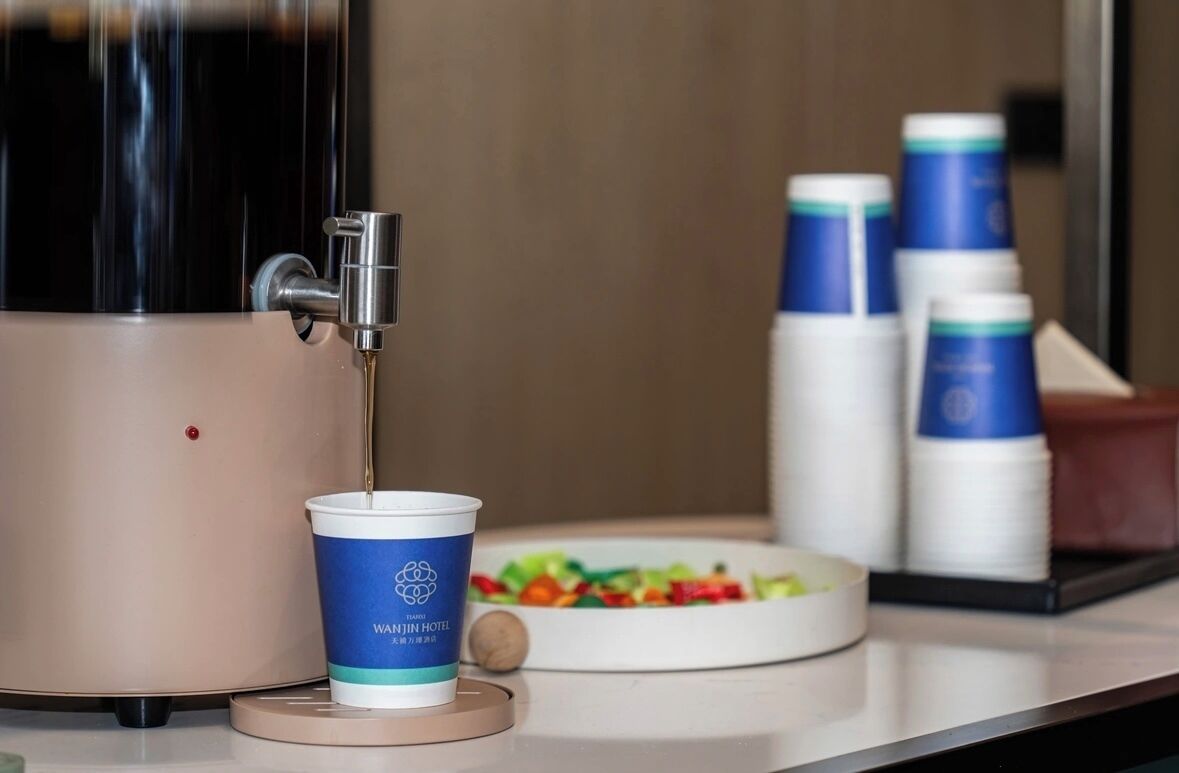 Une machine à café avec une tasse, une assiette remplie d’aliments colorés et des récipients empilés sur un comptoir.