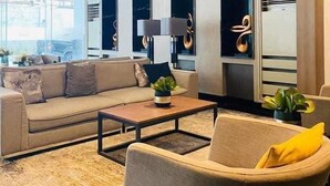 Ein modernes Wohnzimmer mit einer Couch, Sesseln, einem Couchtisch und einem großen Fenster.
