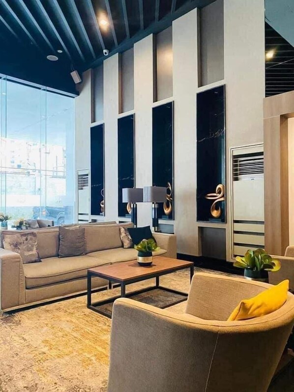 A modern living room with a sofa, armchairs, a coffee table, and a large window. - Air Residences-Contemporary Scandi w/Skyline view (Makati)