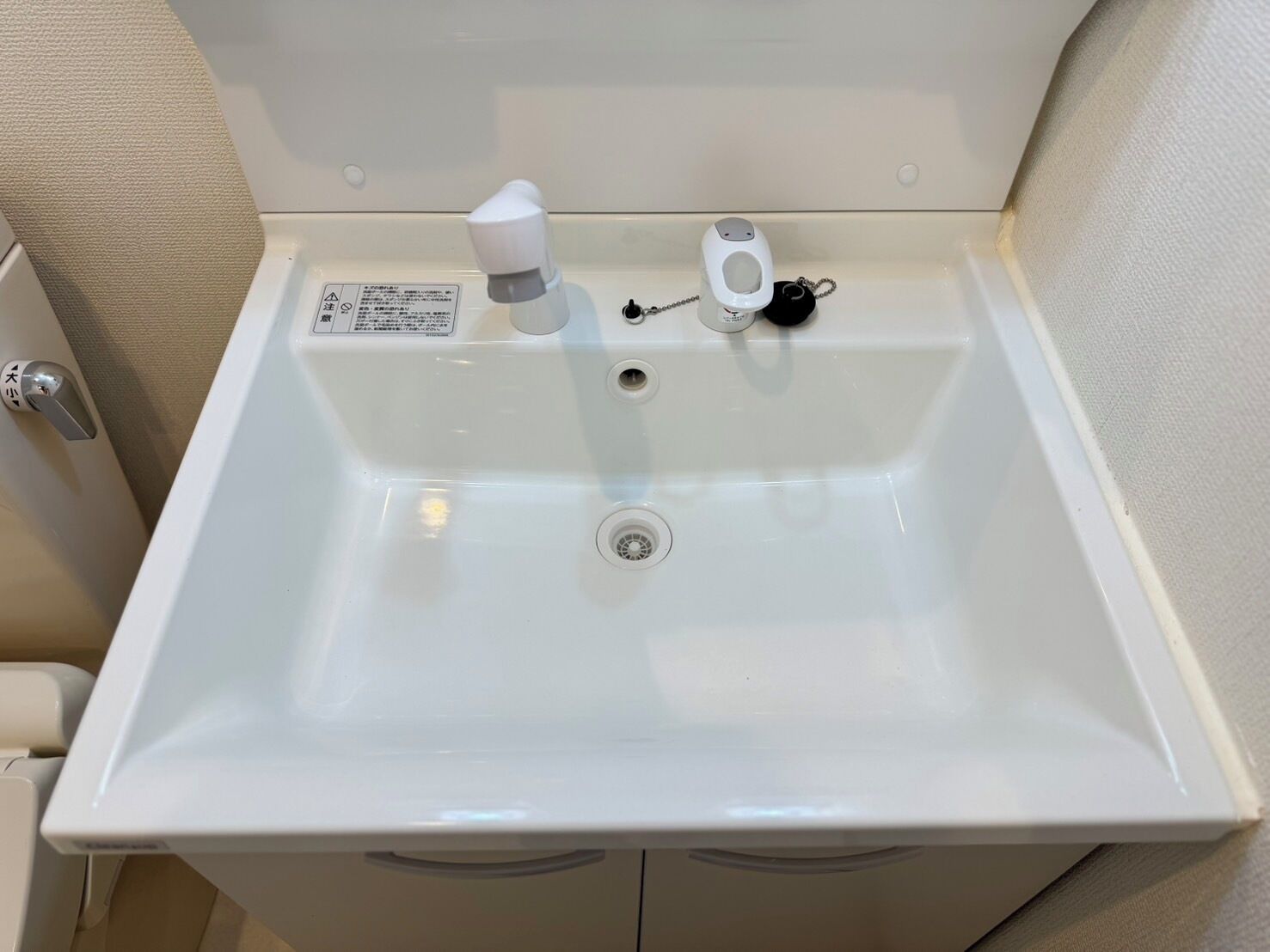 A white sink with a faucet, a soap dispenser, and a drain.