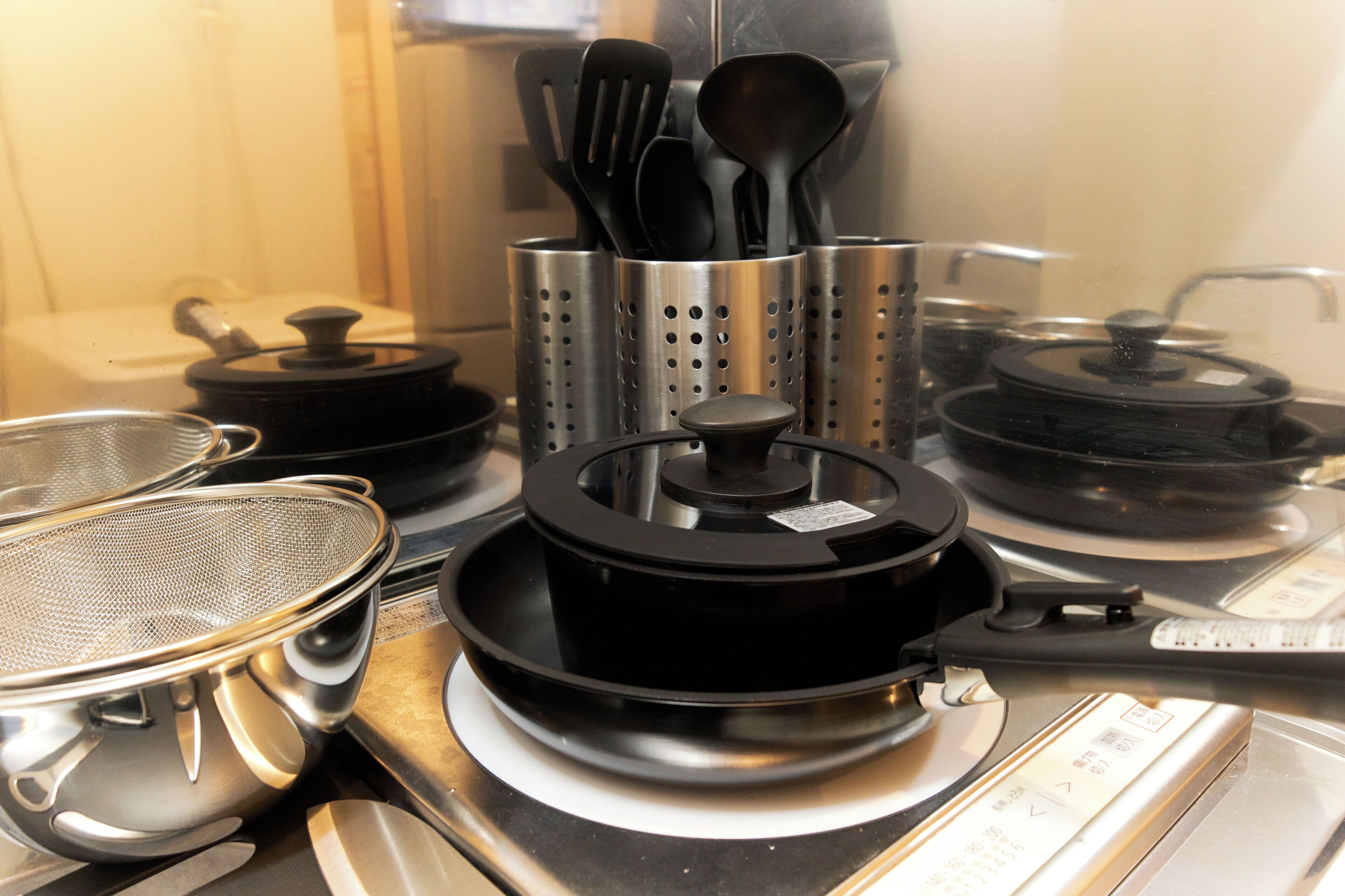 A kitchen with various cooking utensils and appliances, including pots, pans, and a stove.