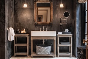 A bathroom with a rustic design, featuring a large mirror, a white sink, and two side tables with baskets. - No77 Leyn Baan The One Group of Hotels  (Galle)