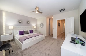 A bedroom with a bed, bedside tables, a desk, and a ceiling fan.
