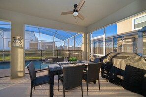 Un patio cubierto con piscina, mobiliario exterior y una parrilla.