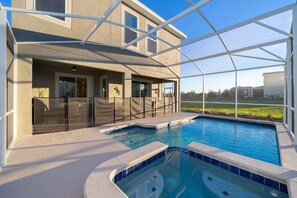 A swimming pool area with a covered patio, a view of the surrounding landscape, and a building with a modern design.