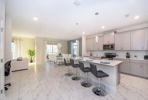 Una cocina moderna con una isla central, taburetes de bar y electrodomésticos de acero inoxidable.