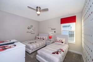 A bedroom with two beds, a ceiling fan, a window with blinds, and Mickey Mouse-themed decor. - Pretty Villa 6Bed/5Bath/Pool/Jacuzzi/18Min Disney (Davenport)