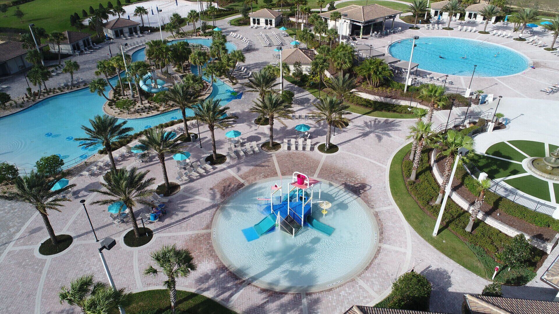 Un complejo turístico con varias piscinas, palmeras y una fuente central.