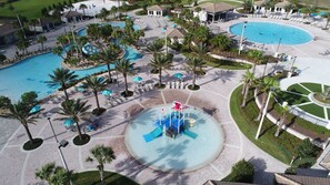 Un complejo turístico con varias piscinas, palmeras y una fuente central.