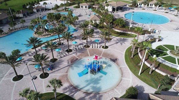 A resort with multiple swimming pools, palm trees, and a central water feature.