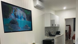 Une cuisine moderne avec des meubles blancs, une cuisinière encastrée et un plan de travail sur lequel se trouve une machine à café.