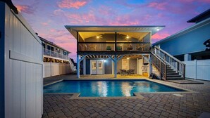 A two-story building with a swimming pool, a balcony, and a staircase leading to the upper level. - Summer Breeze | 5BR Waterfront Home w Heated Pool (North Myrtle Beach)
