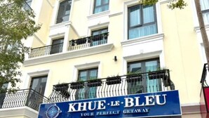 Una entrada de hotel con un letrero que dice "KHUE+LE BLEU YOUR PERFECT GETAWAY".